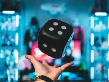 person's left palm about to catch black dice