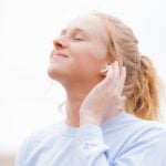 woman in white crew neck shirt covering her face with her hand