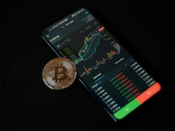 a bitcoin sitting on top of a smart phone
