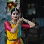 A woman in a yellow and red sari talking on a cell phone