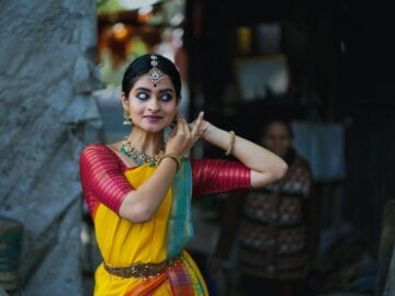 A woman in a yellow and red sari talking on a cell phone