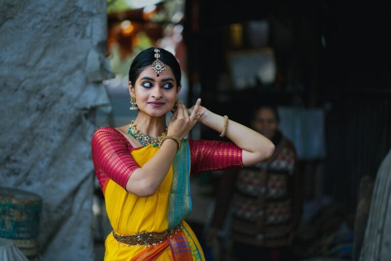 A woman in a yellow and red sari talking on a cell phone