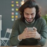 Man smiling while looking at his smartphone