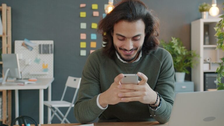 Man smiling while looking at his smartphone