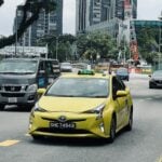a yellow taxi cab driving down a street next to tall buildings