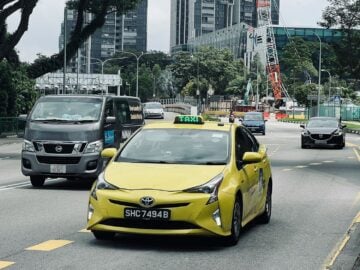 a yellow taxi cab driving down a street next to tall buildings