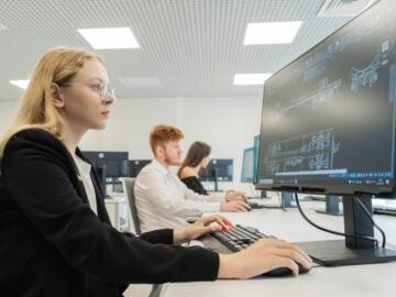 a woman sitting in front of a computer monitor
