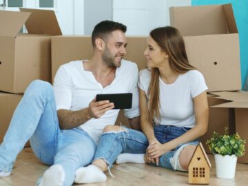 Couple looking at phone surrounded by moving boxes