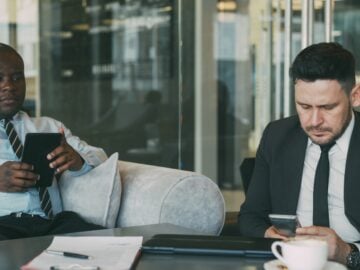 Two businessmen using devices in a modern office.
