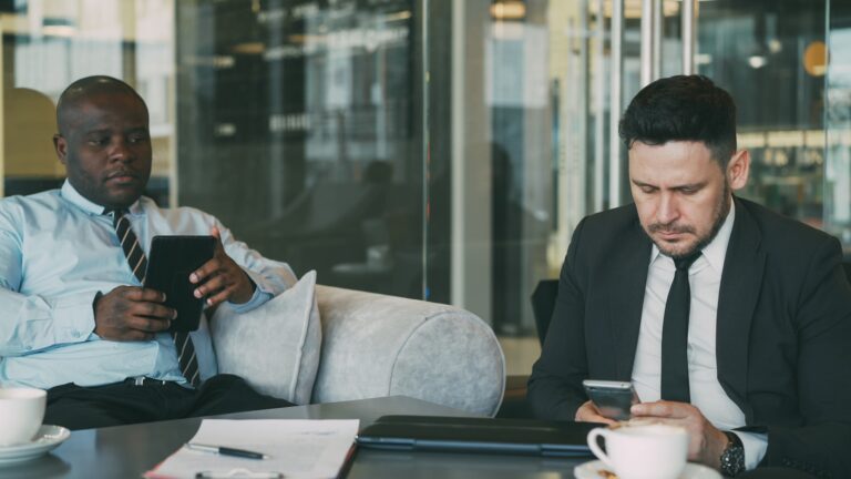 Two businessmen using devices in a modern office.