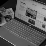 a laptop computer sitting on top of a desk next to a cup of coffee