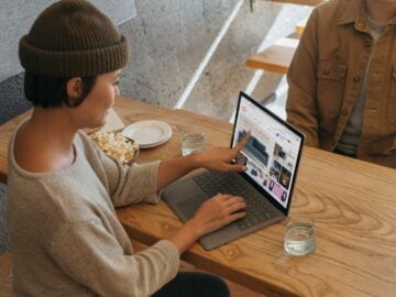 Two people sitting across from each other in an office working on a Surface laptop