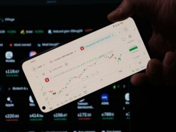 A person holding a cell phone in front of a laptop