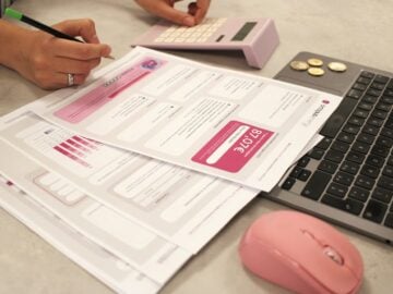 Someone is doing taxes with a calculator and laptop.