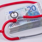 a red stethoscope sitting on top of a pile of money