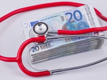 a red stethoscope sitting on top of a pile of money