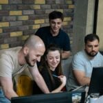 A group of people sitting around a laptop computer