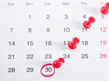 a calendar with red push buttons pinned to it
