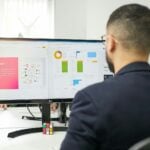 a man sitting at a desk looking at a computer screen