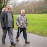 Two older men walking down a wet road