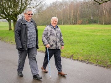 Two older men walking down a wet road