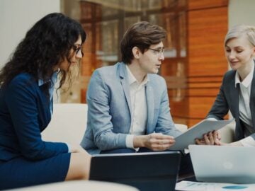 Three professionals discussing documents at a table