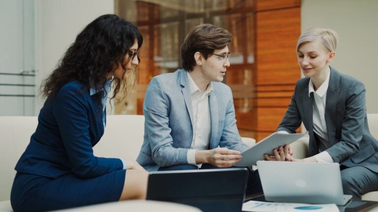 Three professionals discussing documents at a table