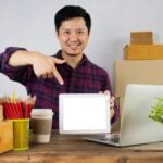 a man pointing at a laptop screen on a desk