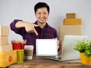a man pointing at a laptop screen on a desk